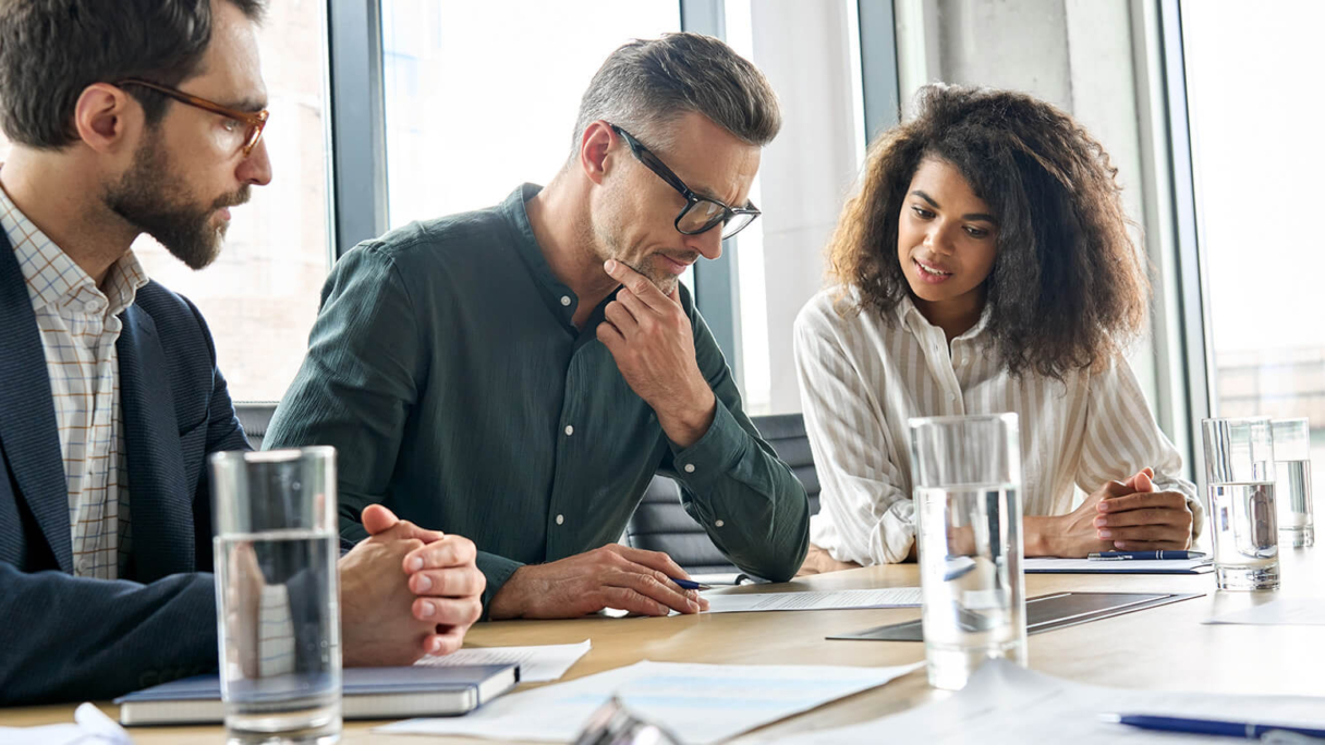 three people discussing something, sat at a desk