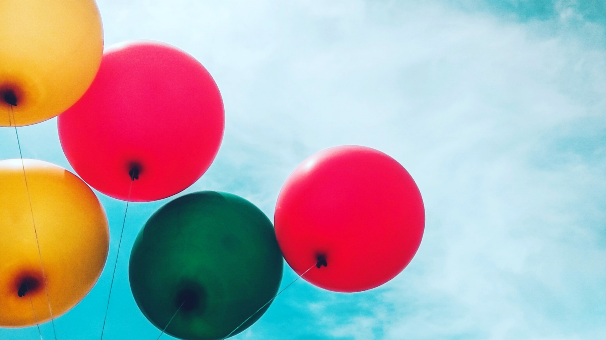 Multi coloured balloons with a blue cloudy sky background