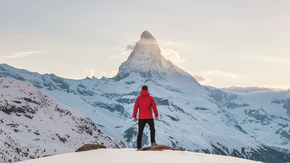 Man standing at the top of a snowy mountain peak